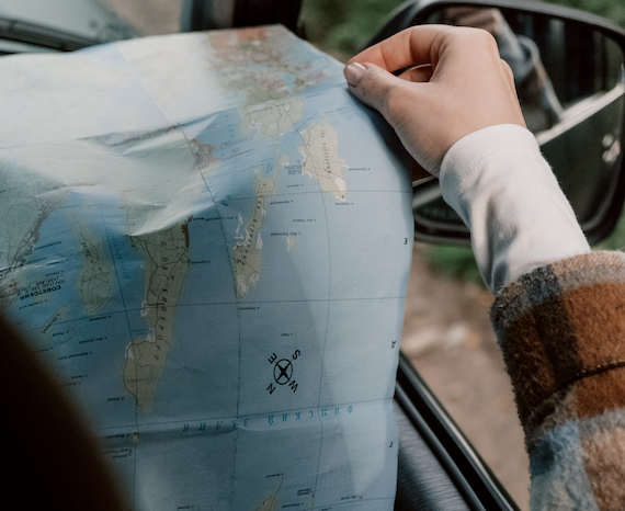 a close shot of a map, with a navigation sign. from Pexels