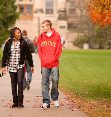 two students walking on campus, framed by yellow autumn leaves